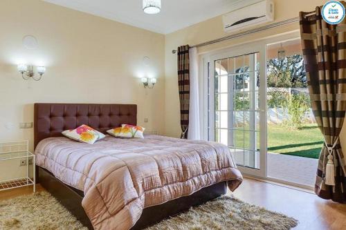 a bedroom with a large bed and a sliding glass door at Villa Mikael - Free Wi-Fi - Aircon - Private Pool by bedzy in Albufeira