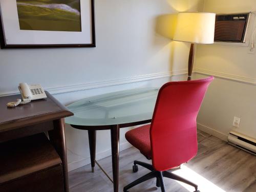 a desk in a room with a red chair and a phone at Alpine Inn Abbotsford in Abbotsford