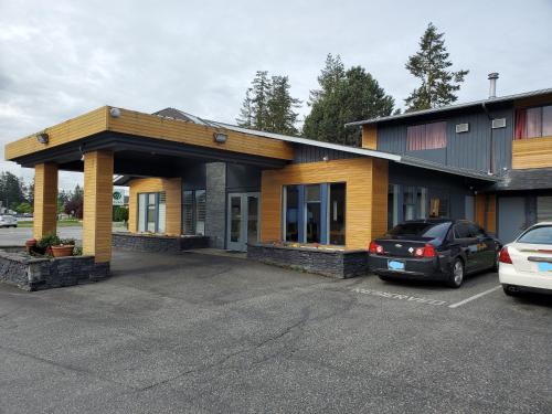 a building with a car parked in a parking lot at Alpine Inn Abbotsford in Abbotsford