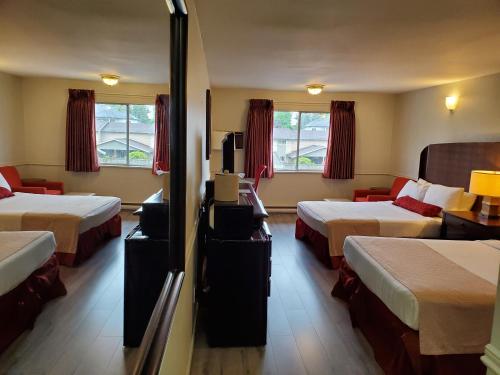 um quarto de hotel com duas camas e uma televisão em Alpine Inn Abbotsford em Abbotsford