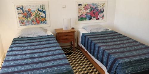two beds in a room with paintings on the wall at Casa da Guarda in Alvor