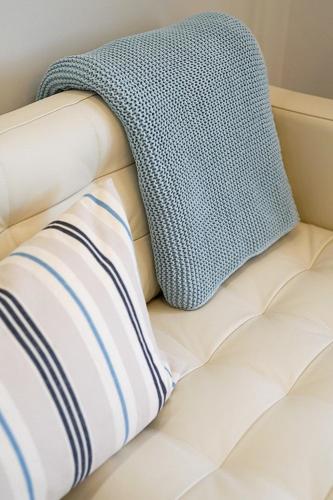 a pillow and a blanket on a couch at RÉS Apartman in Eger