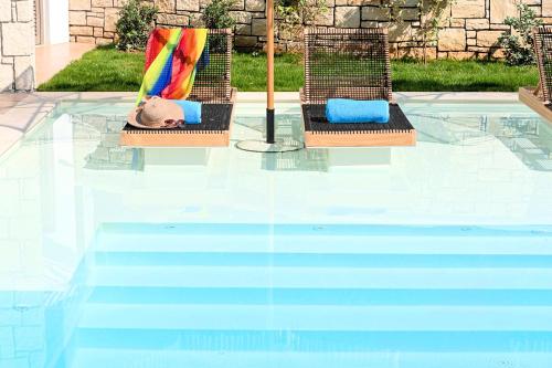 two lawn chairs sitting next to a swimming pool at Blue Lake Villa Heated Pool in Georgioupoli