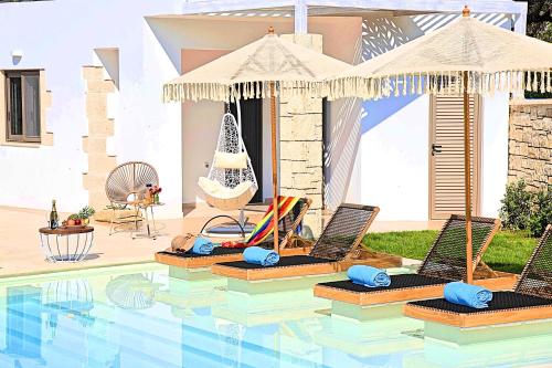 a pool with two lounge chairs and an umbrella at Blue Lake Villa Heated Pool in Georgioupoli