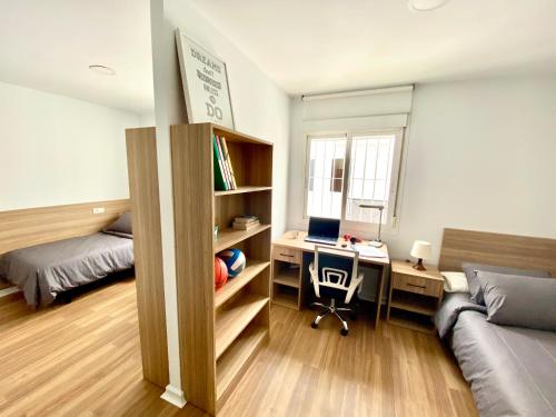 a bedroom with a bed and a desk with a laptop at Micampus Málaga in Málaga