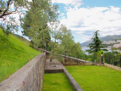 a stone retaining wall with a green field and trees at Comfort Apartments Jazina in Neum