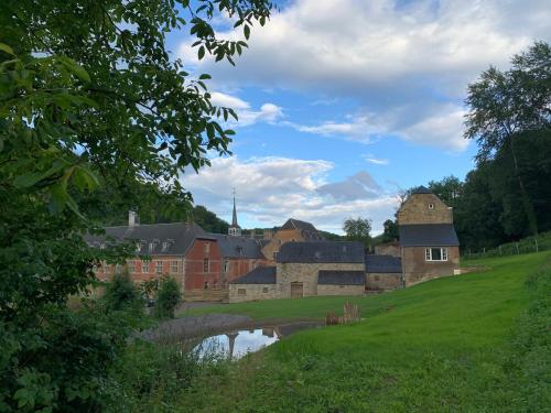 un gruppo di edifici e un fiume in un campo di Abbaye Notre-Dame du Vivier - Le Bief du Vivier a Namur