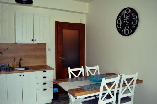 a kitchen with a table and a clock on the wall at U starého jaštera in Veľká Lomnica