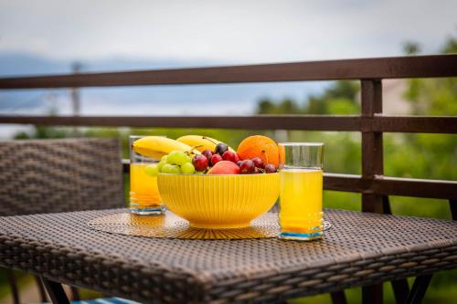 a bowl of fruit on a table with glasses of juice at Apartments Olivia & Navy, Šilo in Šilo