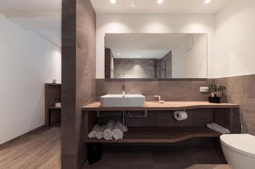 bagno con lavandino e specchio di Hotel Berghang a Collepietra
