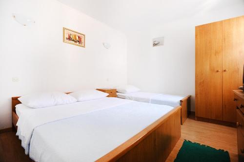 2 letti in una camera con pareti bianche e mobili in legno di Apartments Rejo a Okrug Donji