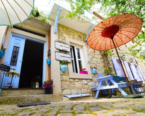 アラカティにあるRue d'Azur Alaçatıのオレンジ傘とベンチ付きの家
