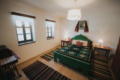 a bedroom with a green bed and two windows at La Mama Anica in Porumbacu de Sus