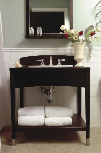 a bathroom with a sink with towels on a shelf at Hôtel Le Rivage in Rosemère