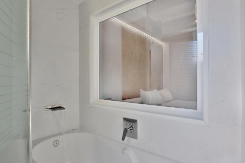 a white bathroom with a mirror and a sink at SunShine Vista al Compás in Córdoba