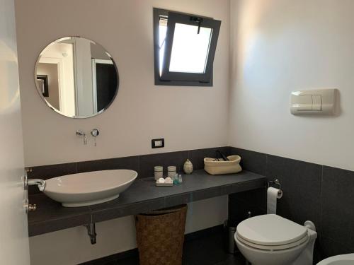 a bathroom with a sink and a toilet and a mirror at Villa Aloe in Menfi