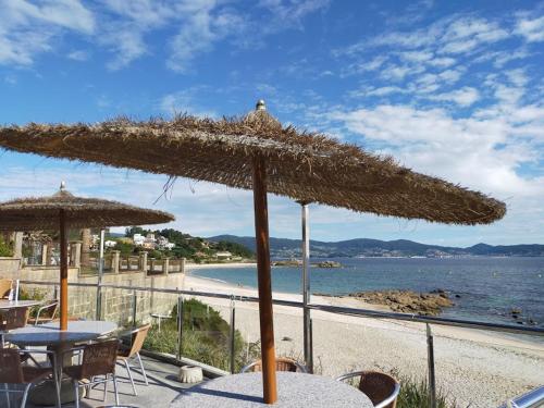 un tavolo con un ombrellone di paglia su una spiaggia di A Postiña ad Areas
