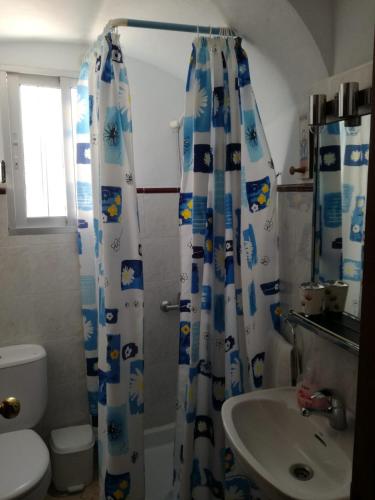 y baño con cortina de ducha y lavamanos. en Casa López, en Vejer de la Frontera