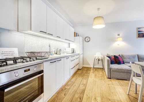 a kitchen with white cabinets and a living room at Apartament Albatros in Władysławowo