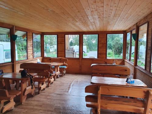 a room with wooden tables and benches and windows at Cicha Przystań in Nowy Dwór Gdański