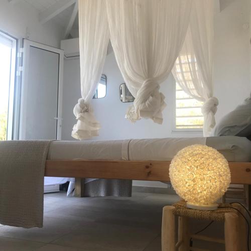 a bedroom with a bed with white curtains and a table at The Grey Houses in Grand-Bourg