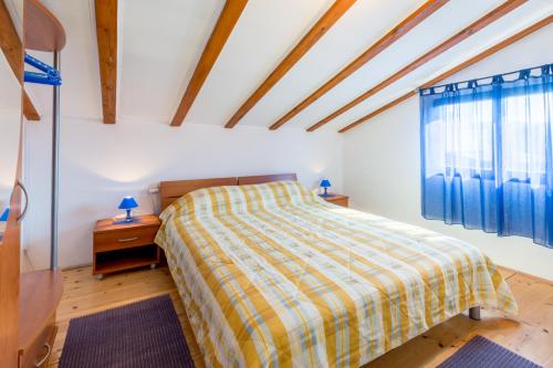 a bedroom with a bed and a window with blue curtains at Vacation house Milka in Milna