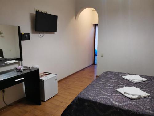 a room with a bed and a desk and a television at Guesthouse Aragats in Adler