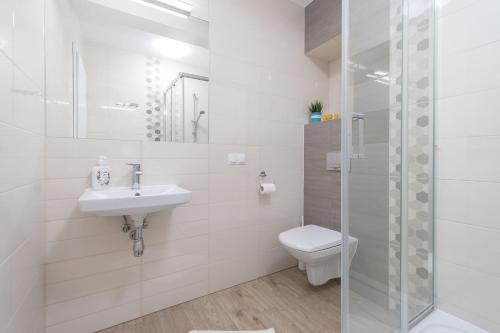 a bathroom with a toilet and a sink and a shower at Plażowe Apartamenty Grzybowo in Grzybowo