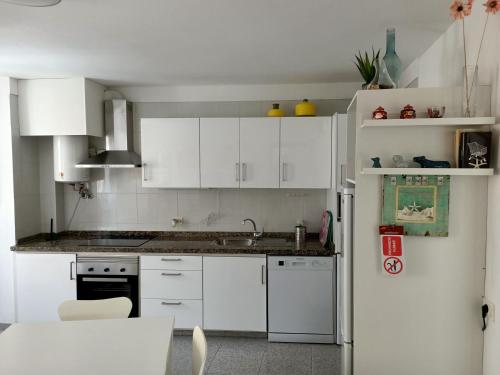 uma cozinha com armários brancos e um frigorífico branco em Casa Mary em Granadilla de Abona