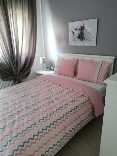 a bedroom with a pink and white bed with a window at Apartman Jezdić 2 in Banja Koviljača