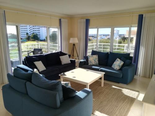 a living room with blue couches and a table at Apartamento Vila Marachique in Alvor