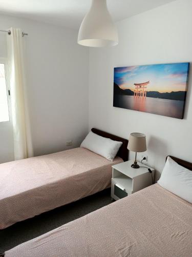 a bedroom with two beds and a painting on the wall at Casa Mary in Granadilla de Abona