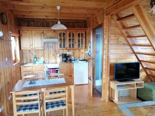 a kitchen in a log cabin with a television at PILGRIM domek gościnny w Gietrzwałdzie na Warmii in Gietrzwałd