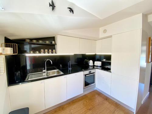 a kitchen with white cabinets and a sink at Unique apartment by MyPlaceForYou, in the center of Lisbon with views over the city and the Tagus river in Lisbon