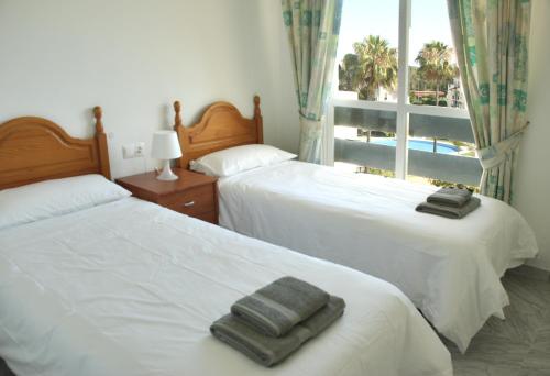 two beds with towels on them in a bedroom with a window at Great 2 Bedroom Apartment Near Puerto Banus in Marbella