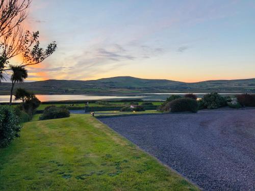 a gravel road leading to a lake at sunset at Skellig Port Accomodation - 2 Bed Apartment in Portmagee
