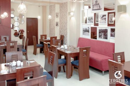 un restaurante con mesas de madera y un sofá rosa en Hotel San Sebastián Loja, en Loja