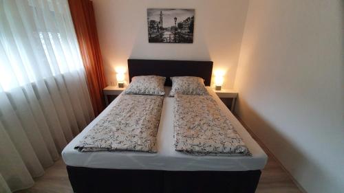 two beds in a small room with two lamps at Sam's Place in Kreuzwertheim