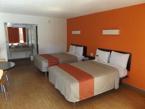 two beds in a hotel room with orange walls at FairBridge Inn Express North Lima in North Lima