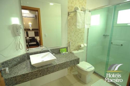 a bathroom with a sink and a toilet and a mirror at Hotel Maestro Premium Cascavel in Cascavel