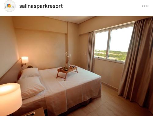 a bedroom with a bed with a table and a window at Salinas Parks in Salinópolis