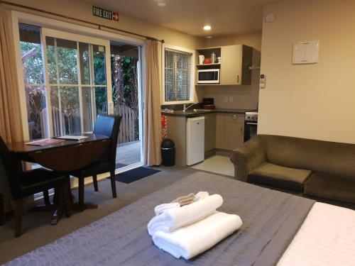 a room with a bed and a table and a kitchen at Cranford Cottages and Motel in Christchurch
