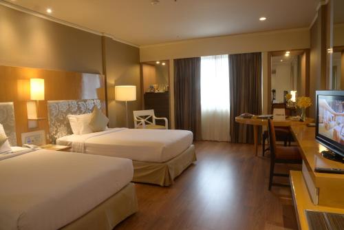 a hotel room with two beds and a flat screen tv at Royal Princess Larn Luang - SHA Extra Plus in Bangkok