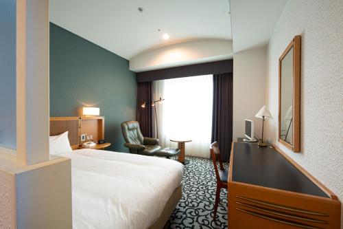 a hotel room with a bed and a desk and chair at Hotel Nagoya Garden Palace in Nagoya