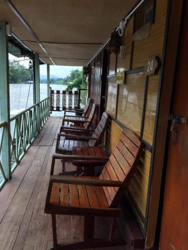 a row of wooden benches sitting on a deck at แพแหม่มทัวร์ in Sai Yok