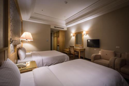 a hotel room with two beds and a chair at Guide Hotel Zhongli Zhongzheng in Zhongli