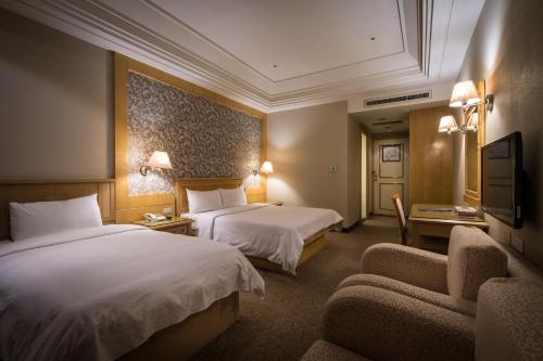 a hotel room with two beds and a chair at Guide Hotel Zhongli Zhongzheng in Zhongli