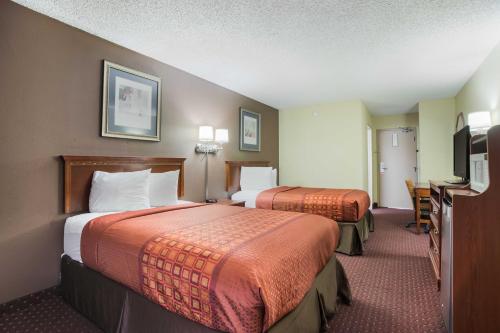 a hotel room with two beds and a desk at Americas Best Value Inn Tulsa I-44 in Tulsa