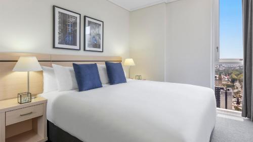 a bedroom with a large white bed with blue pillows at Oaks Brisbane Festival Suites in Brisbane