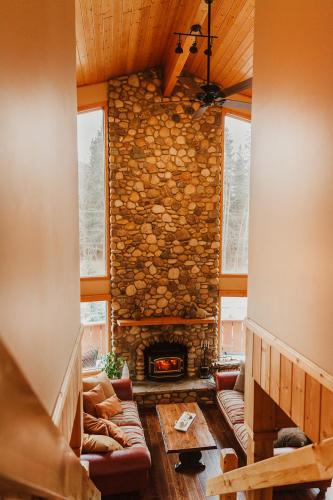 a living room with a stone wall and a fireplace at Ambleside Lodge Bed & Breakfast in Canmore